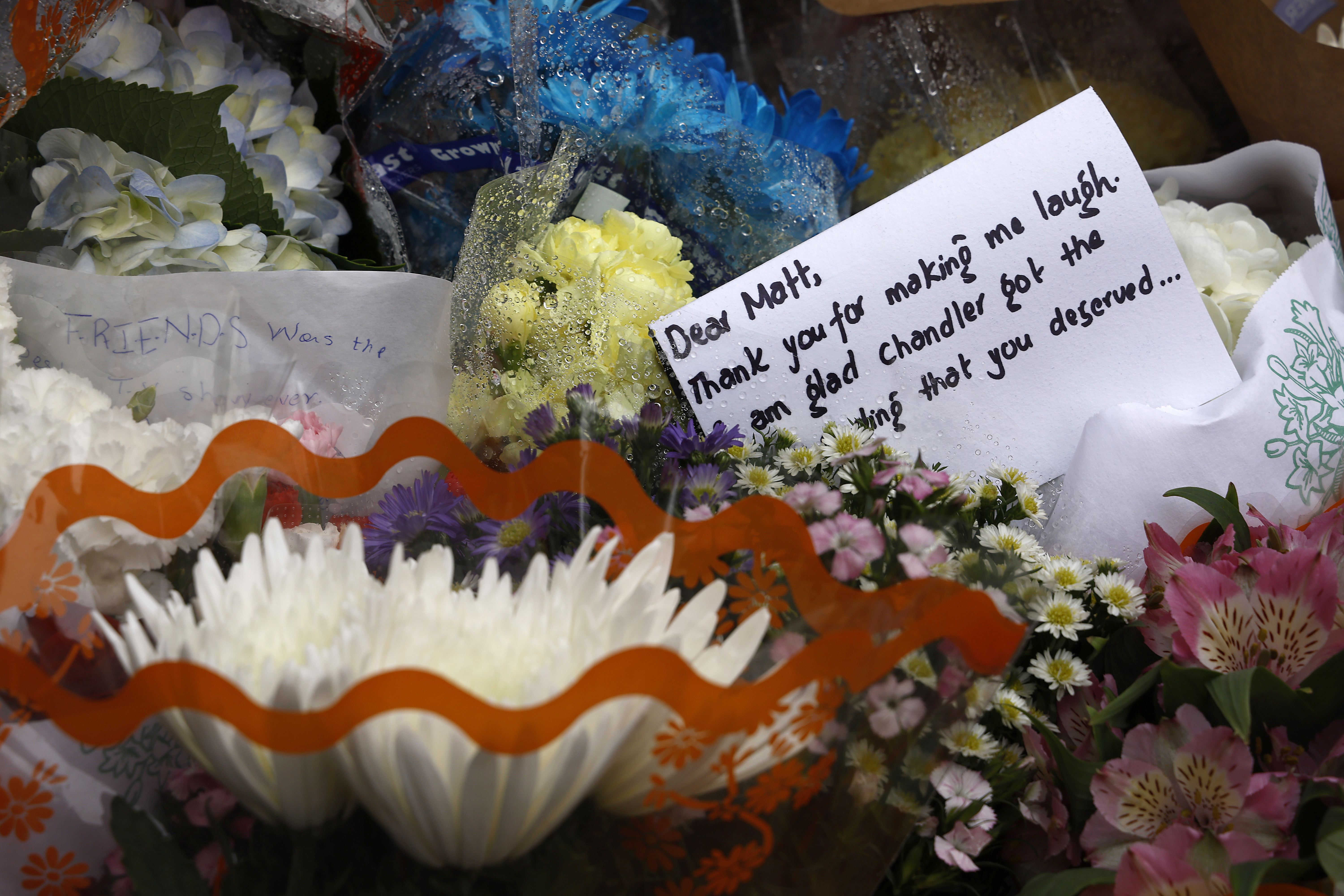 NEW YORK, NEW YORK - OCTOBER 30: Flowers and a note are placed at the memorial as fans pay tribute to the late actor Matthew Perry outside "Friends" building  on October 30, 2023 in New York City. (Photo by John Lamparski/Getty Images)