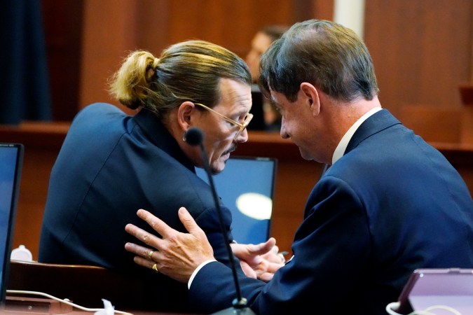 Johnny Depp hablando con su abogado Ben Chew, en la sala del tribunal de circuito del condado de Fairfax en Fairfax, Virginia, en mayo de 2022.