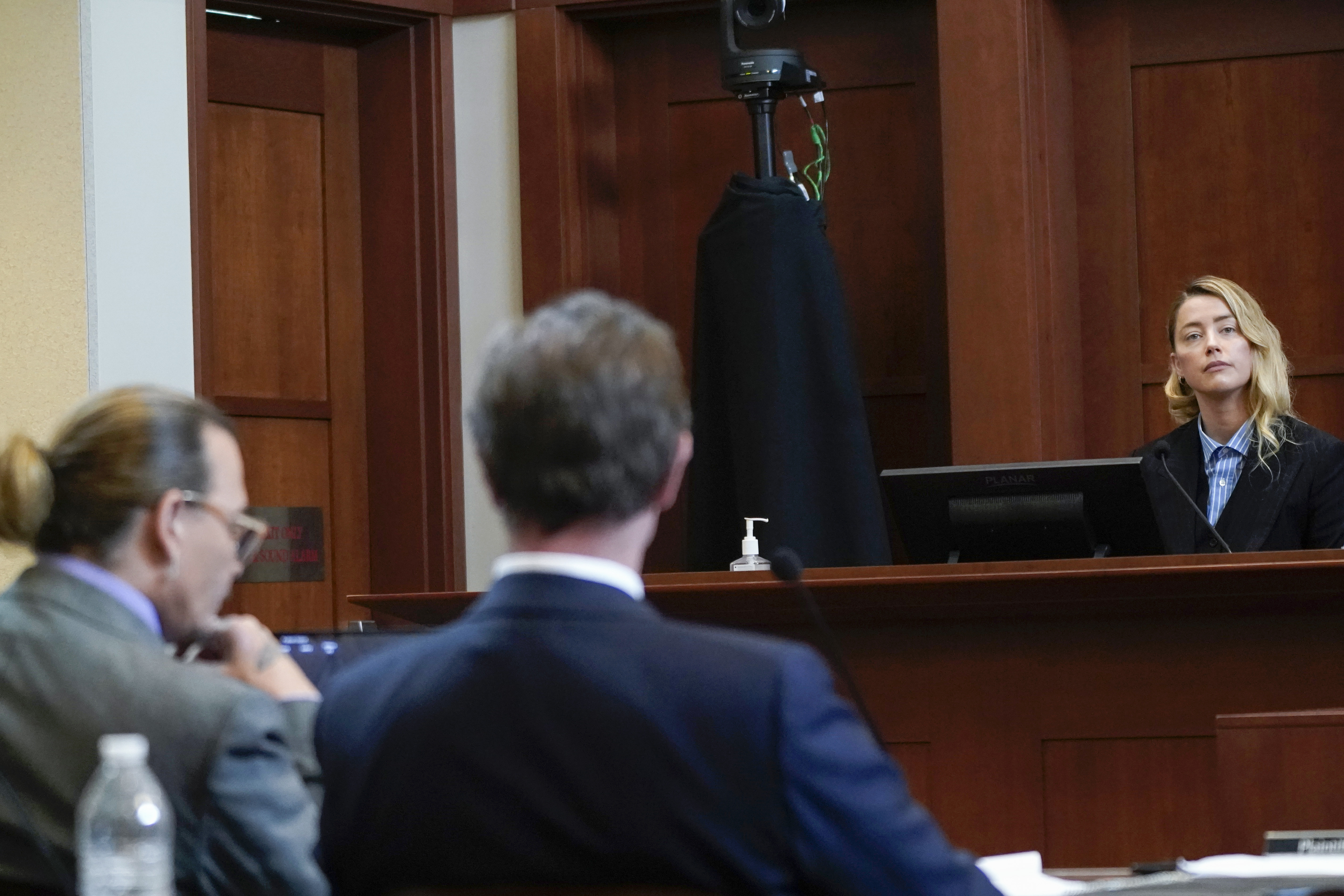 Johnny Depp escucha a la actriz Amber Heard quien testifica en la sala del Tribunal de Circuito del Condado de Fairfax en Fairfax, Virginia, en mayo de 2022.