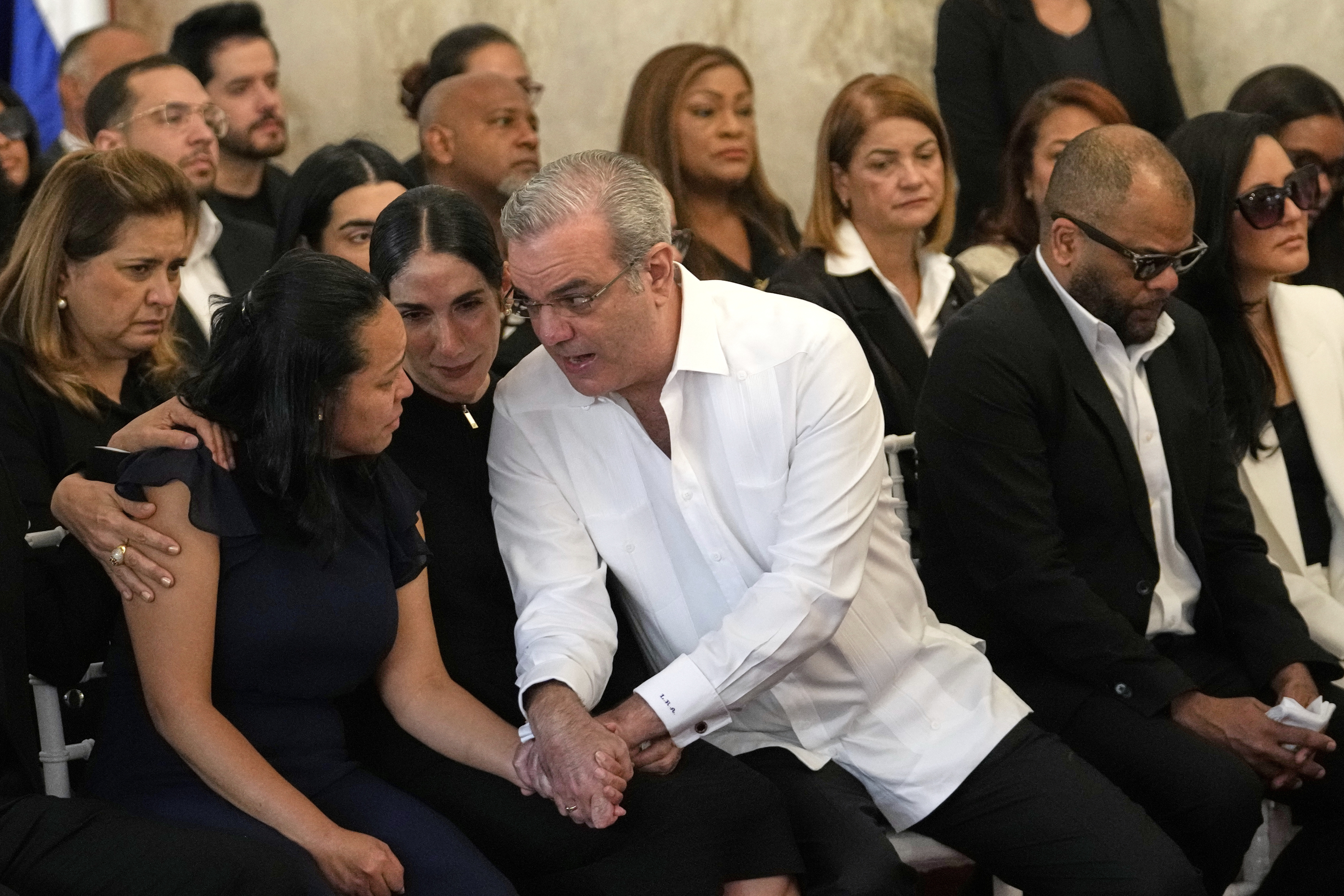El presidente de República Dominicana, Luis Abinader (centro derecha), y su esposa, Raquel Arbaje Soni, hablan con la familia del cantante dominicano Rubby Pérez, quien falleció al derrumbarse el techo del club nocturno Jet Set mientras ofrecía un concierto, durante el velorio en el Teatro Nacional Eduardo Brito en Santo Domingo, República Dominicana, el jueves 10 de abril de 2025. (Foto AP/Matias Delacroix)