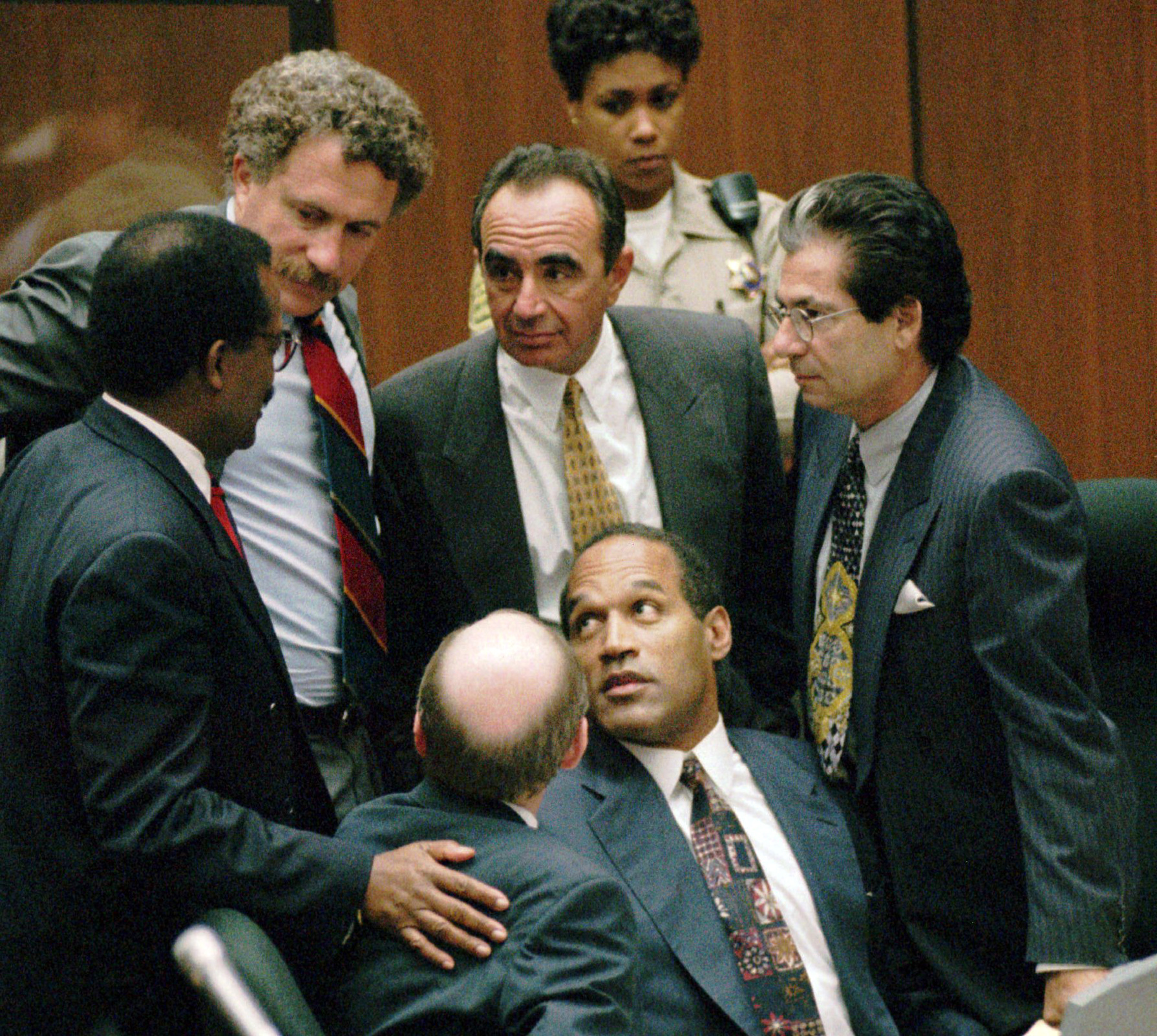 En esta foto de archivo del 28 de septiembre de 1995, O.J. Simpson está rodeado por sus abogados defensores del "Dream Team" (de izquierda a derecha): Johnnie L. Cochran Jr., Peter Neufeld, Robert Shapiro, Robert Kardashian y Robert Blasier, sentados a la izquierda, al final de los alegatos de la defensa en Los Ángeles. Para una generación anterior, O.J. Simpson era un símbolo de tensión racial y justicia desigual. Si bien los problemas en torno a la raza y la actuación policial persisten hoy en día, el simbolismo racial de Simpson se considera en gran medida una reliquia. (AP Photo/SamMircovich, Pool, File)