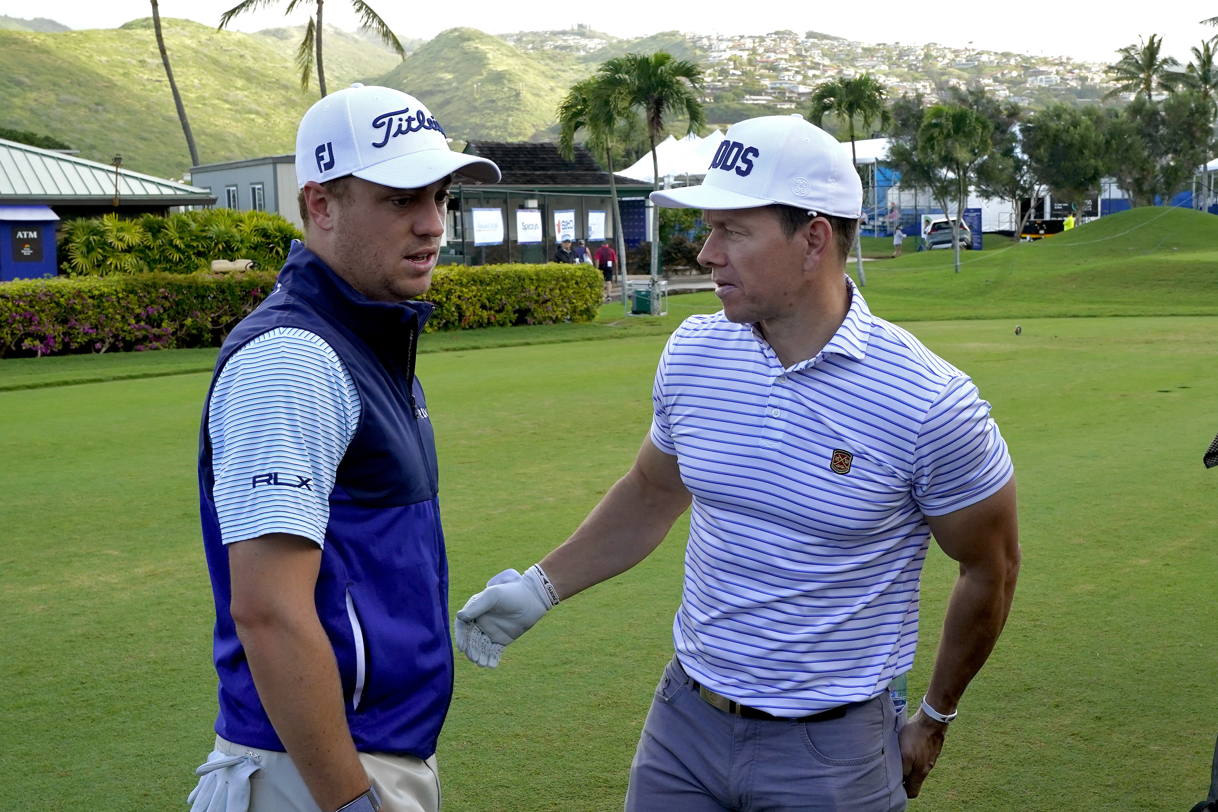 Justin Thomas, a la izquierda, conversa con el actor Mark Wahlberg durante el torneo de golf pro-am del Sony Open PGA Tour, el miércoles 8 de enero de 2020, en el Waialae Country Club de Honolulu. (Foto AP/Matt York).